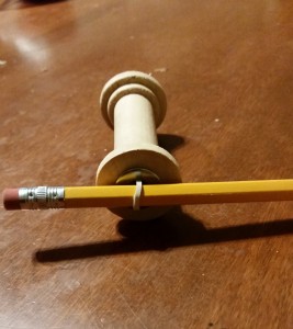 Side view of rubber band threaded through metal washer and looped around the pencil